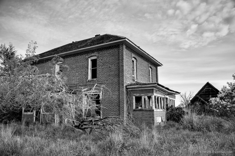 A black and white photograph of an old brick farmhouse in rural Douglas County, Washington.