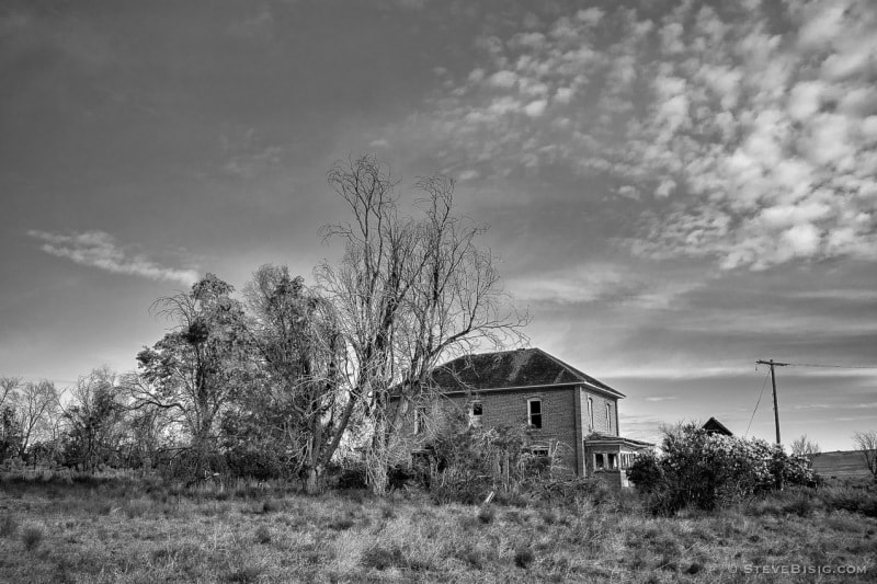 A black and white photograph of old abandoned farmstead in rural Douglas County, Washington.