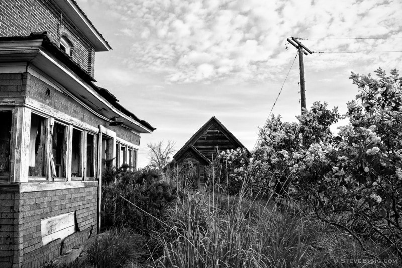 A black and white photograph of an old brick farmhouse in rural Douglas County, Washington.