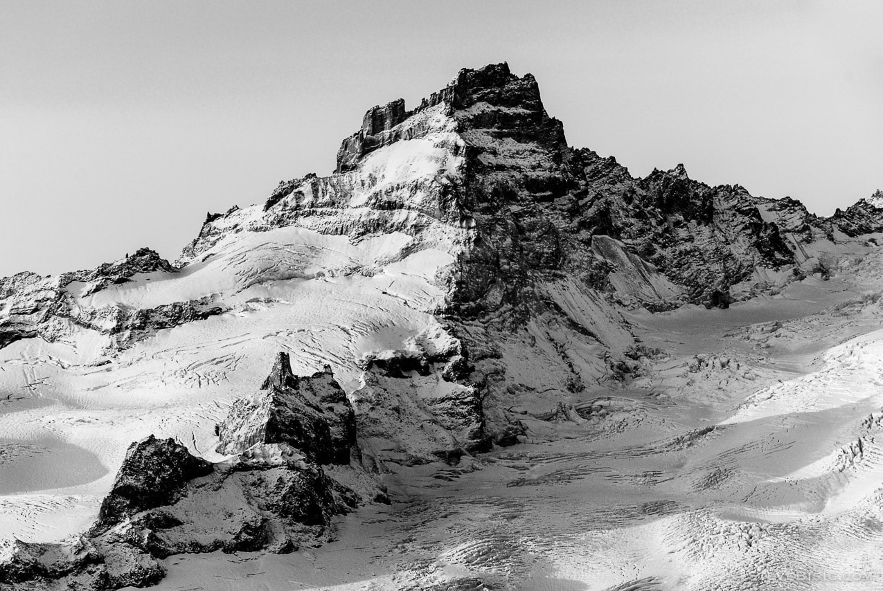 A black and white photograph of the rising sun shining on Little Tahoma (Mount. Rainier) as viewed from Sunrise, Mount Rainier National Park, Washington