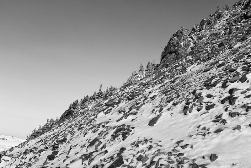 A black and white photograph of a rocky hillside covered with fresh Autumn snow. Near Sunrise at Mount rainier National Park, Washington.