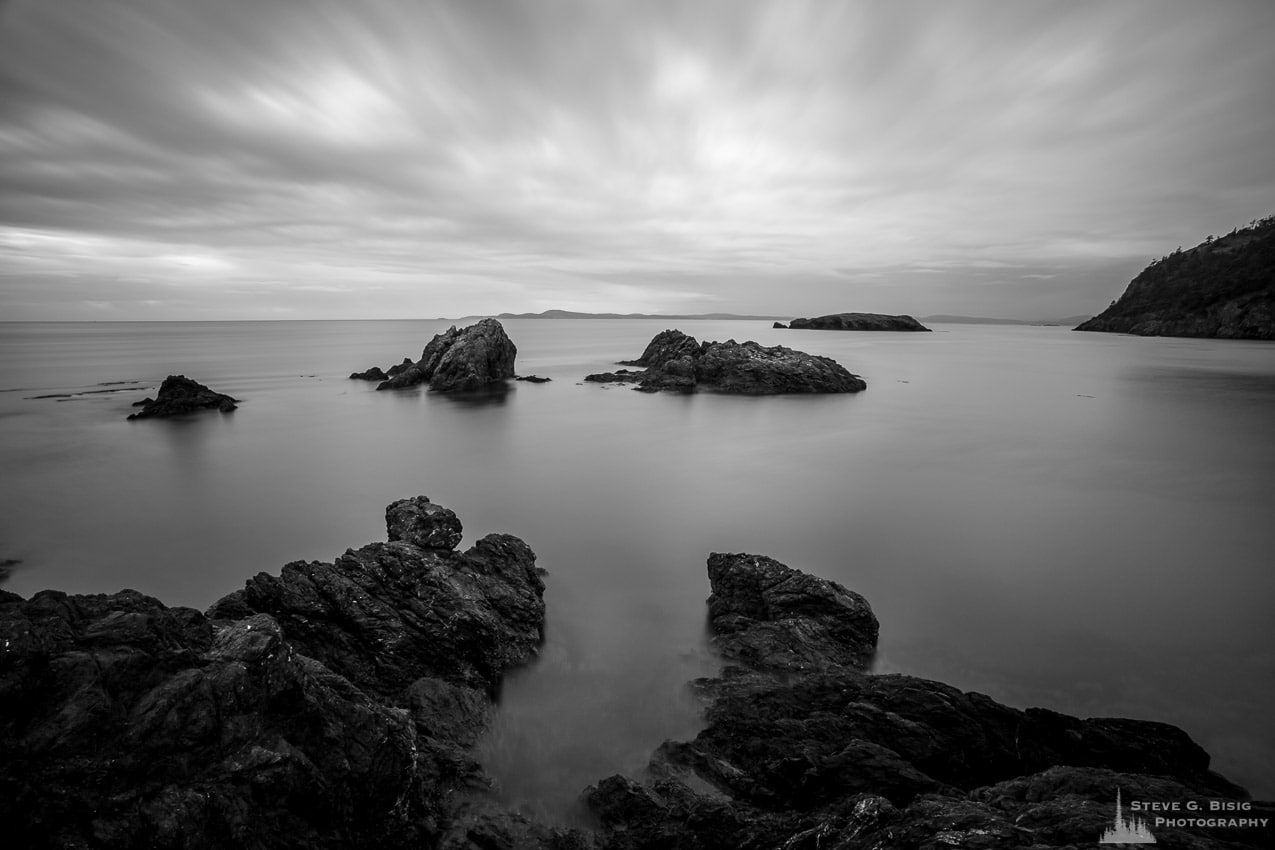 A black and white, long exposure landscape photograph of rocky coastline (Urchin Rocks) near Rosario Beach at Deception Pass State Park on Fidalgo Island, Washington.