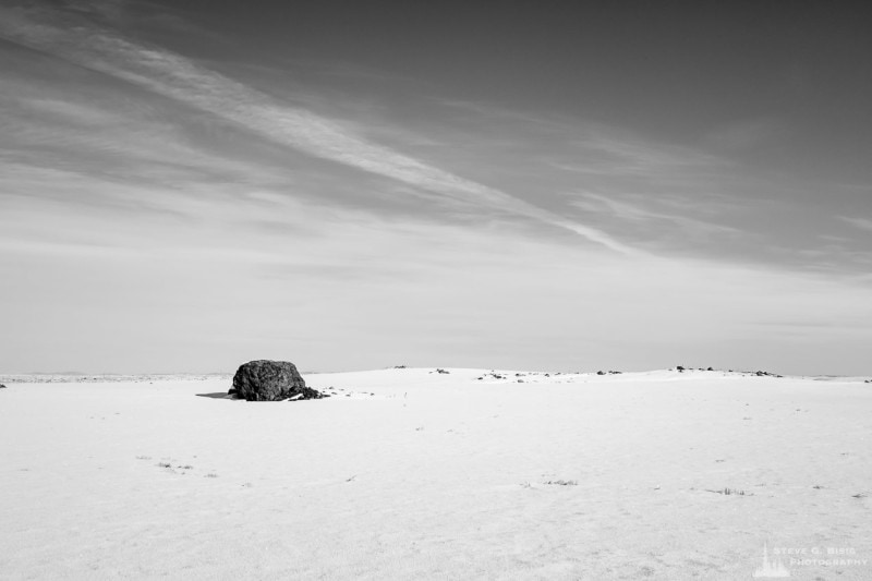 A black and white photograph of a lone boulder in a snow covered field near State Route 174 in rural Douglas County, Washington.