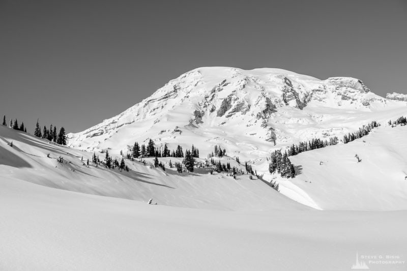 A black and white landscape photograph of Mount Rainier as captured on a sunny winter day in the Paradise area of Mount Rainier National Park, Washington.