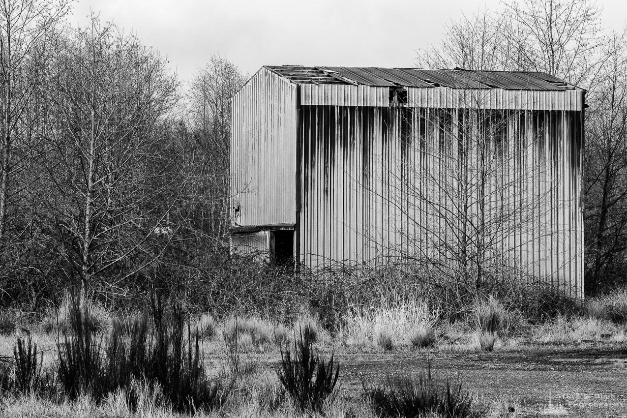 A black and white urban photograph of an abandoned rusty metal building in the industrial district of Hoquiam, Washington.