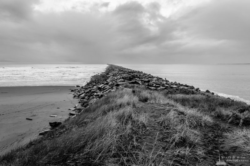 A black and white landscape photograph of the South Jetty between the Pacific Ocean and Grays Harbor at Westhaven State Park near Westport, Washington.