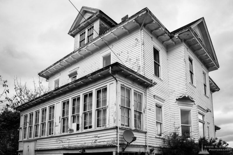 A black and white photograph of a old white house overlooking South Bend, Washington.