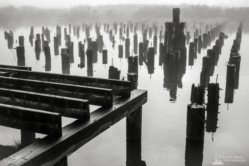 One of a series of black and white photographs of an old wharf along the Willapa River on a foggy autumn morning in Raymond, Washington.