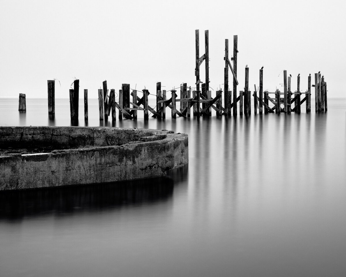 A black and white photograph of old ruins from the Dickman Mill on the Puget Sound along Ruston Way, Tacoma, Washington.