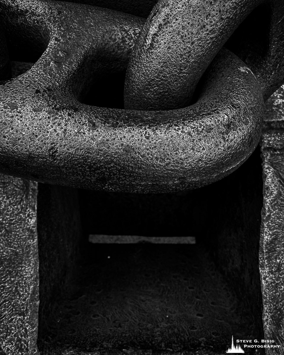 A close-up black and white mobile photograph of a ship chain on display at the Columbia River Maritime Museum in Astoria, Washington.