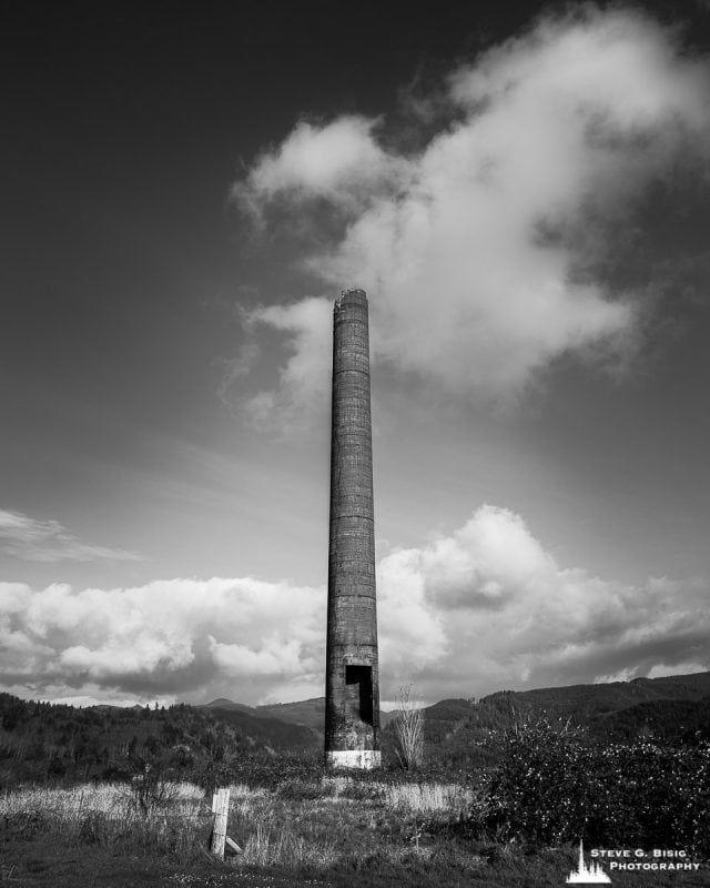 A black and white fine art landscape photograph of the old Hammond Lumber Company smokestack (circa 1927) in Garibaldi, Oregon.