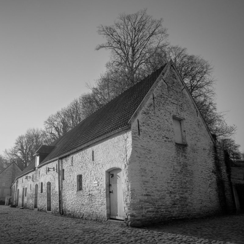 A black and white photograph of the old agricultural buildings at Rouge Cloître, Auderghem, Belgium.