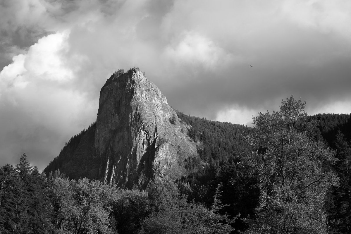 A black and white landscape photograph of the evening light shining on Tower Rock near Cispus Center, Washington.