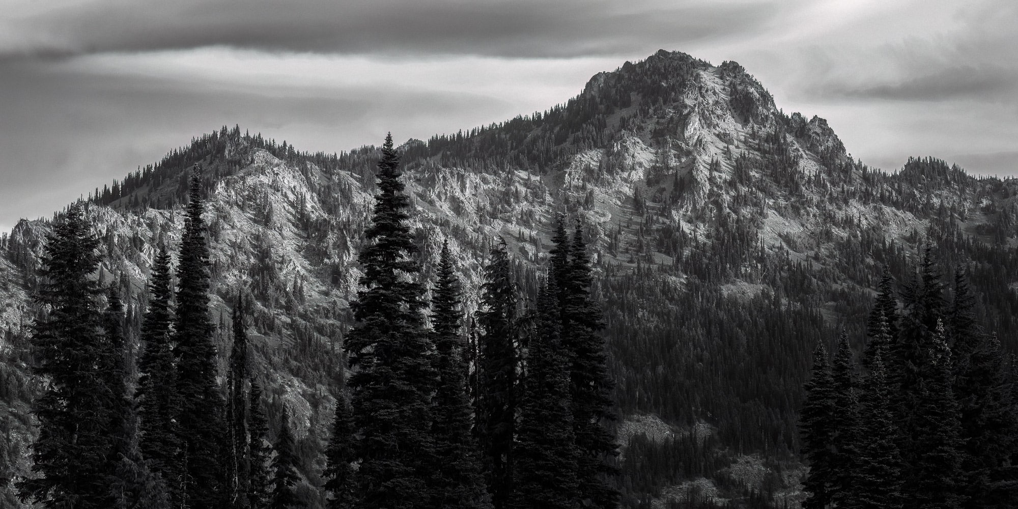 A black and white panoramic landscape photograph of 6,904 foot Chinook Peak as viewed  along the Naches Peak Loop trail near Chinook Pass, Washington.