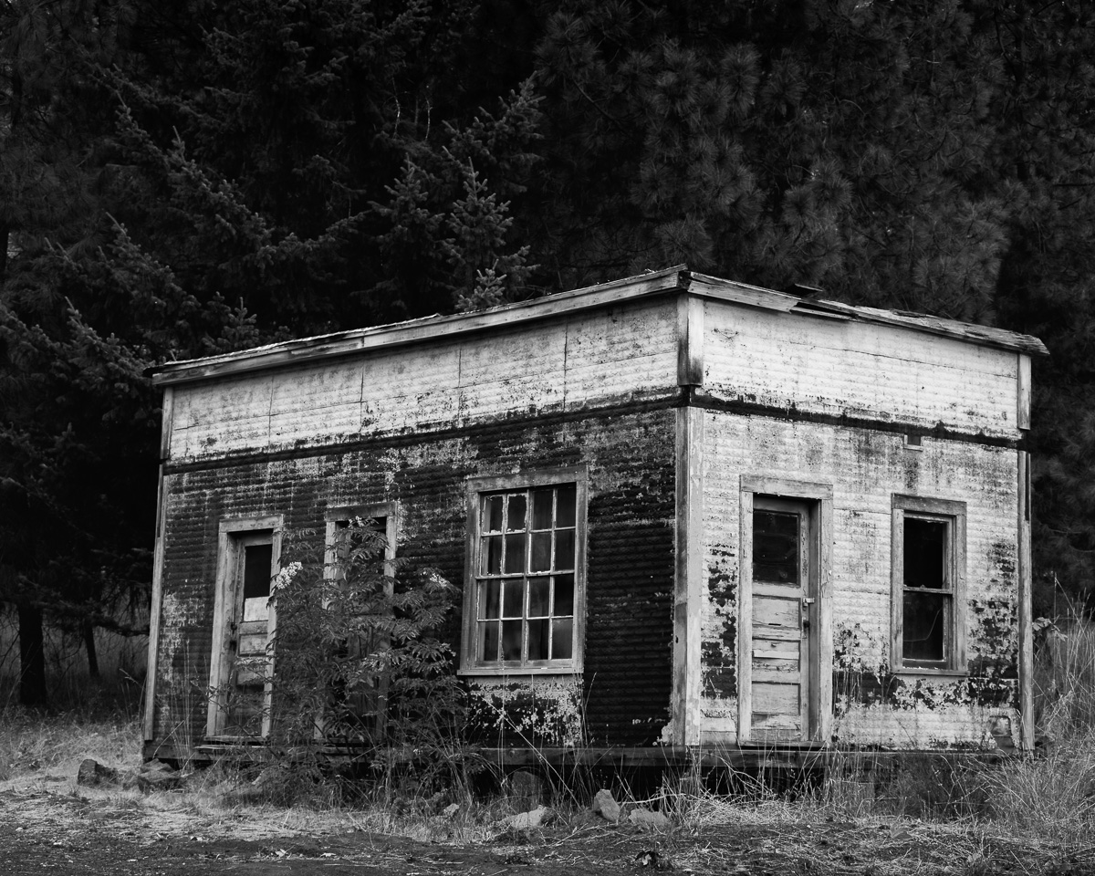 Echoes of the past linger in this black-and-white portrayal of an old post office. Encased by creeping vegetation and cloaked in peeling paint, the building is a testament to time's relentless march. Shadows dance across its surface, inviting viewers to actively uncover the secrets etched into its walls and imagine the lives it once sheltered.