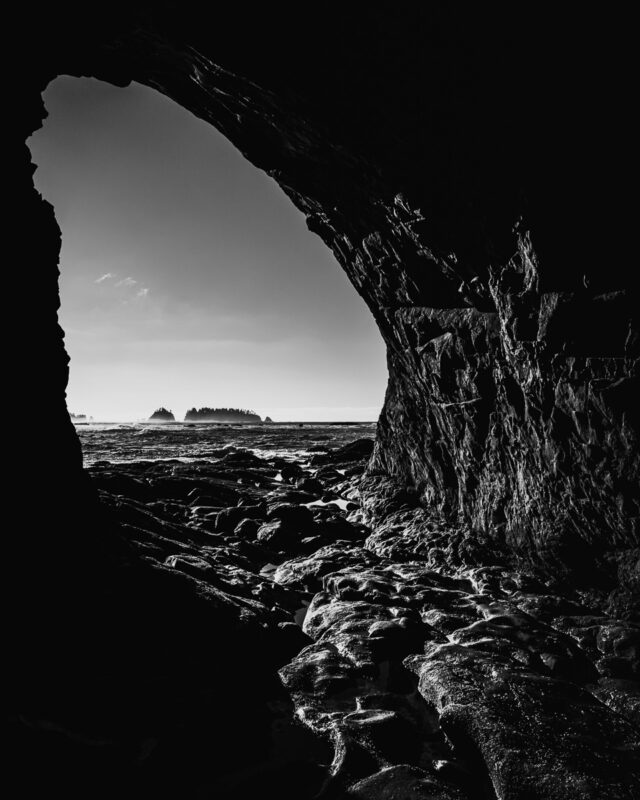 Experience the tranquil allure of Rialto Beach through this captivating black-and-white photograph. The natural cave frames the rugged coastline, inviting contemplation and connection with the serene beauty of Washington's landscape.