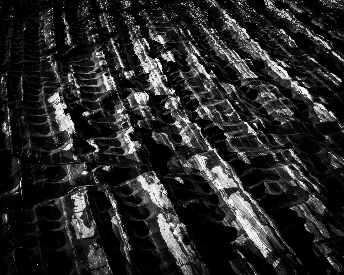 Explore the intricate patterns etched by nature along the rugged coastline of Rialto Beach, Washington. This black-and-white piece captures the textured dance of light and shadow on rock formations, offering a serene glimpse into the Pacific Northwest's timeless beauty.