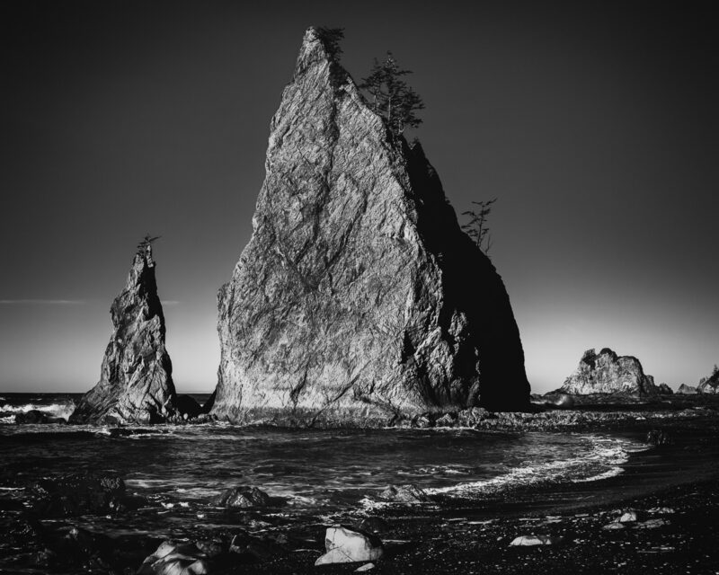 Experience the tranquil power of Rialto Beach in this black-and-white seascape. The dramatic sea stacks stand silently against the vast ocean, embodying nature's timeless beauty.