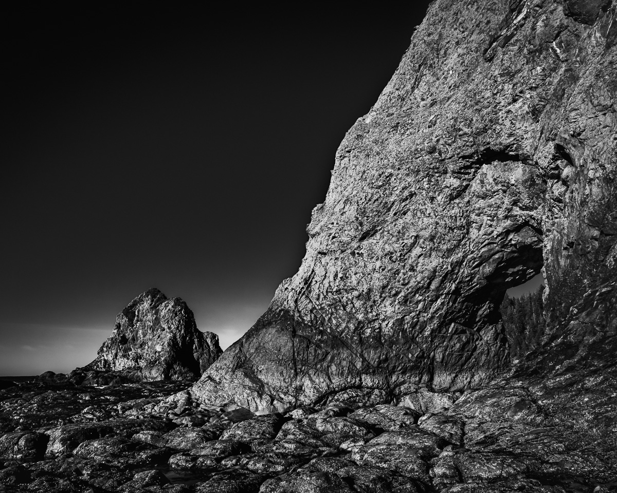 Experience the rugged beauty of Washington's coastline in this dramatic black-and-white photograph. The textured rocks and stark contrasts evoke a sense of timelessness and tranquility.