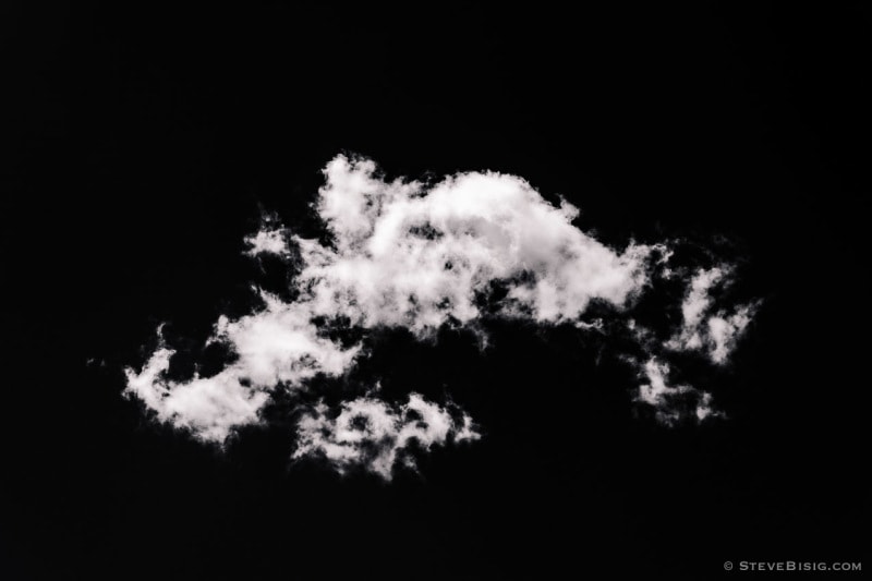 A black and white photograph of a lone cloud high over the Washington Cascade Mountains.