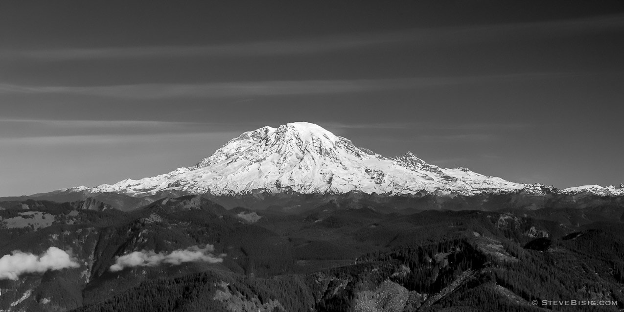 A black and white panoramic photograph of a snow-capped Mt Rainier as viewed from Burley Mountain Lookout in Lewis County, Washington.