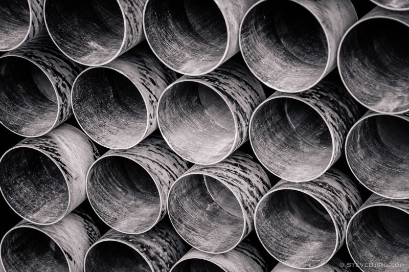 A black and white photograph of a stack of PVC pipes at a construction site in Seattle, Washington.