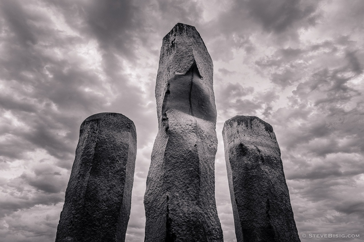 A black and white fine art photograph of three stone pillars with dark clouds in the background located in the Chinese Reconciliation Park in Tacoma, Washington.