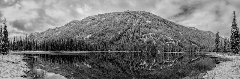 A black and white panoramic photograph of Tacquala Lake in Kittitas County, Washington after a early Fall snowfall.